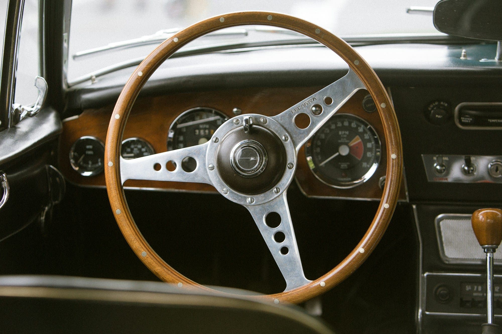El volante de madera y el salpicadero de un coche clásico.